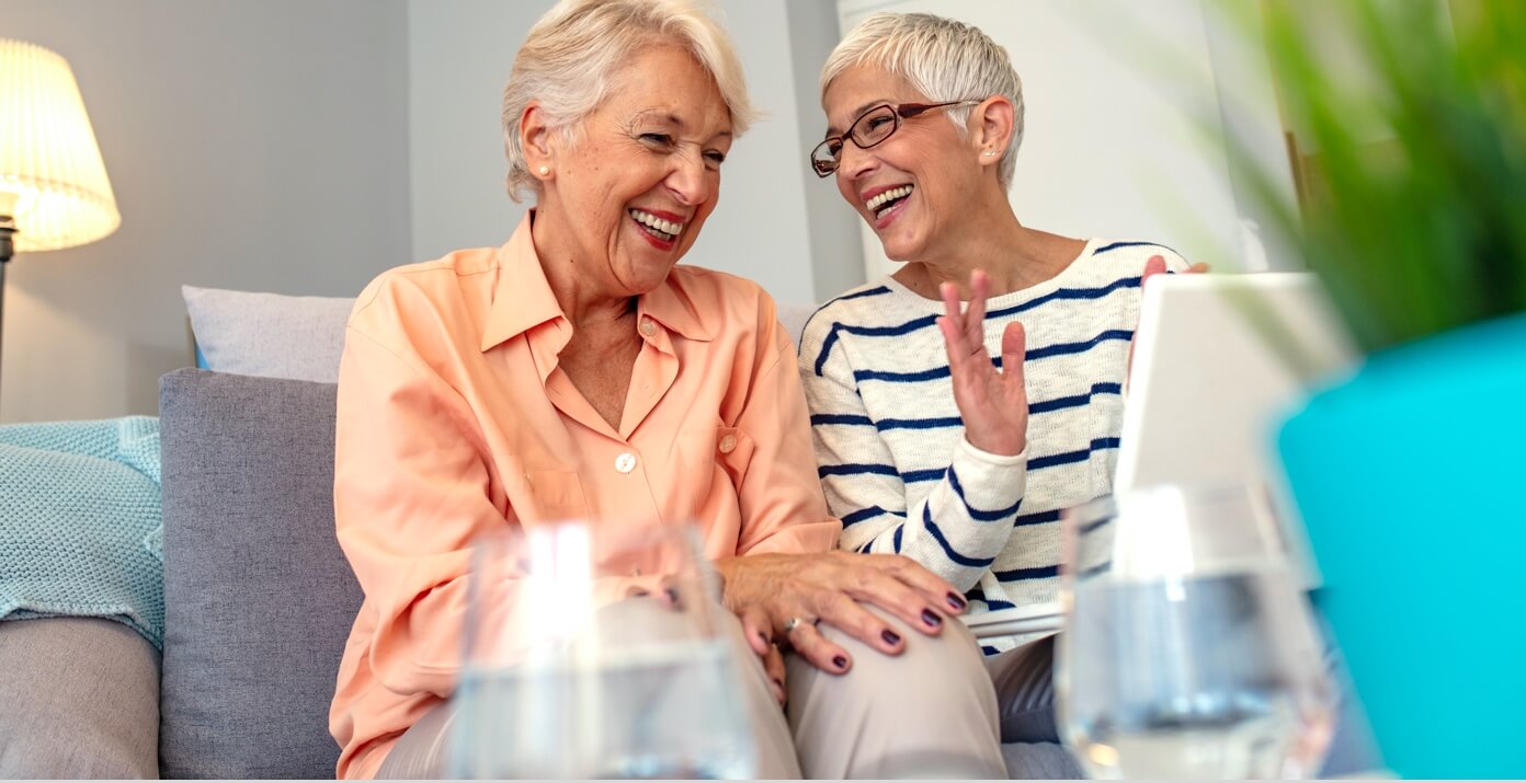 Two women sitting on couch laughing